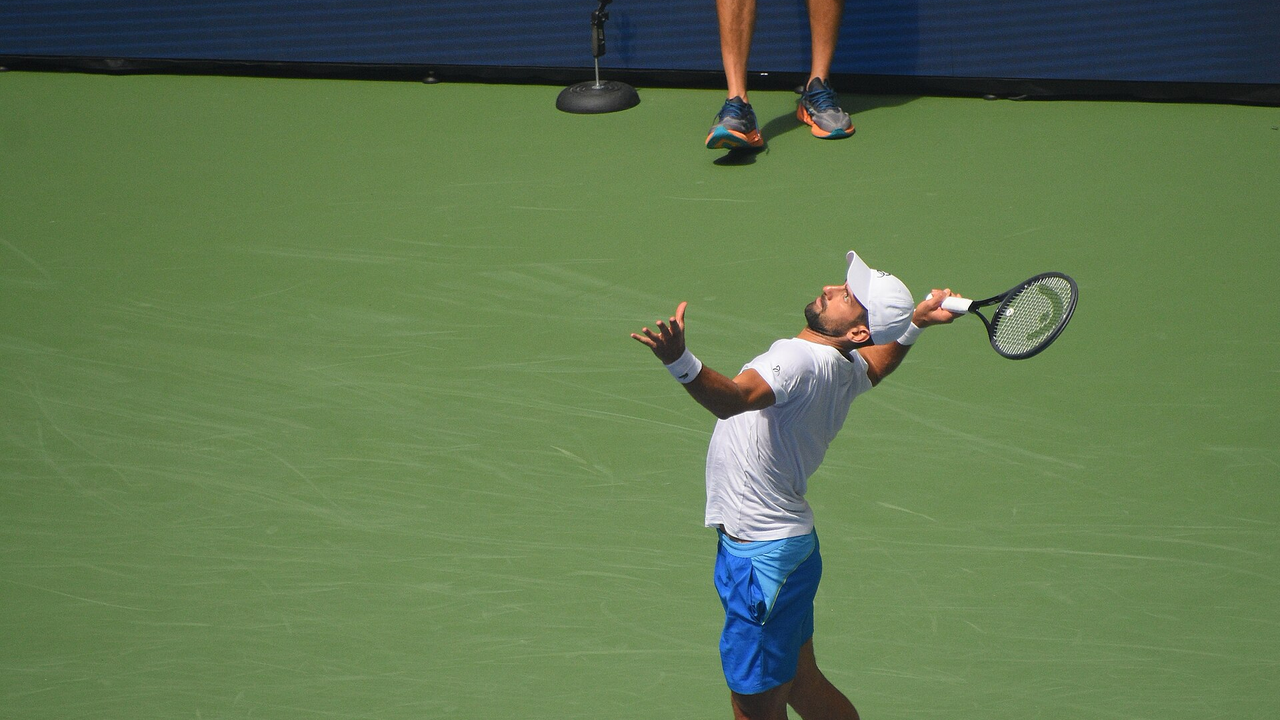 Novak Djokovic practises his serve on a hard court before the US Open