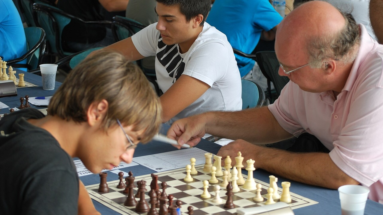Chess players compete at several boards in a tournament hall