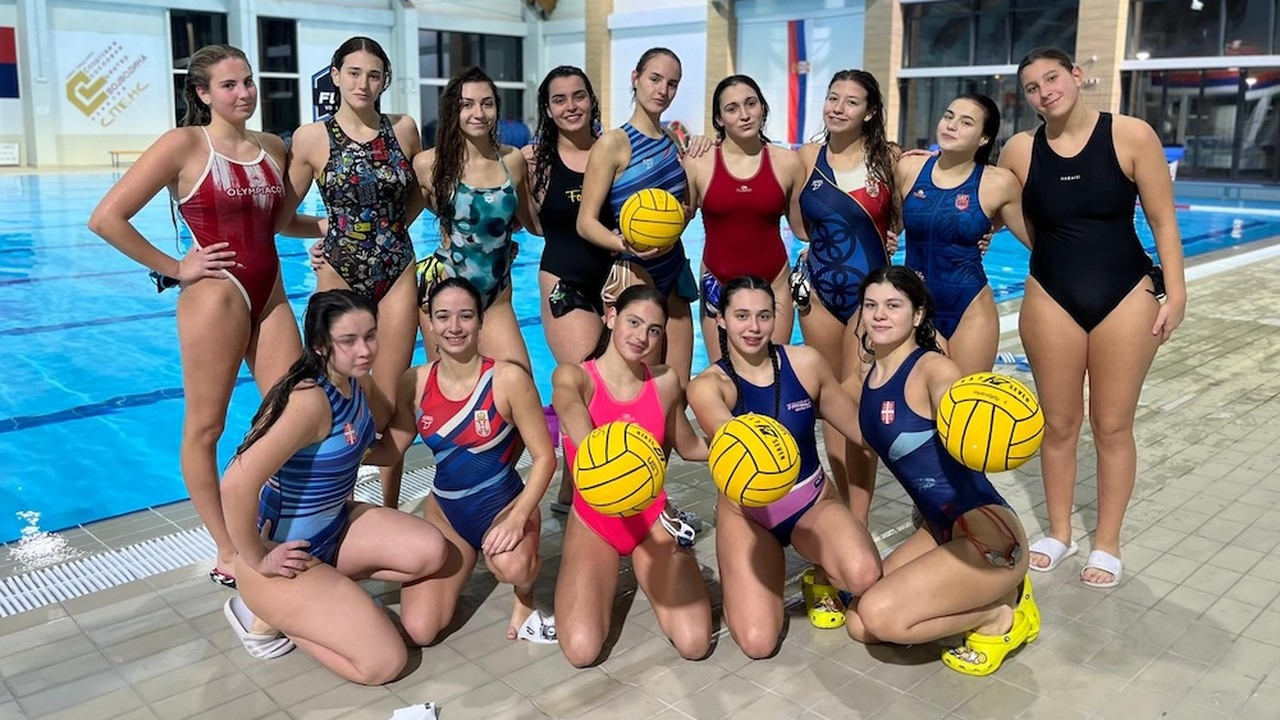 Serbian women's water polo players pose beside an indoor pool