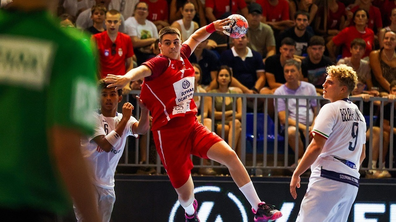 A Serbia handball player shoots over a defender