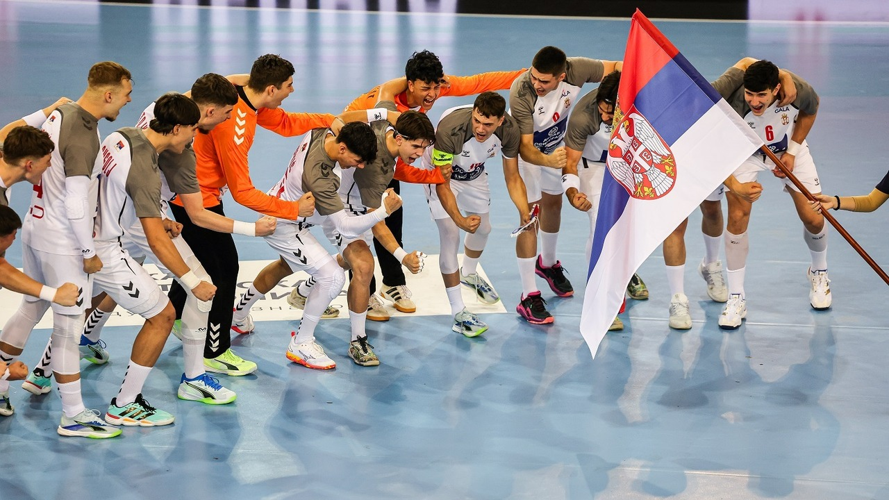Serbia under-18 handball players gather around the national flag