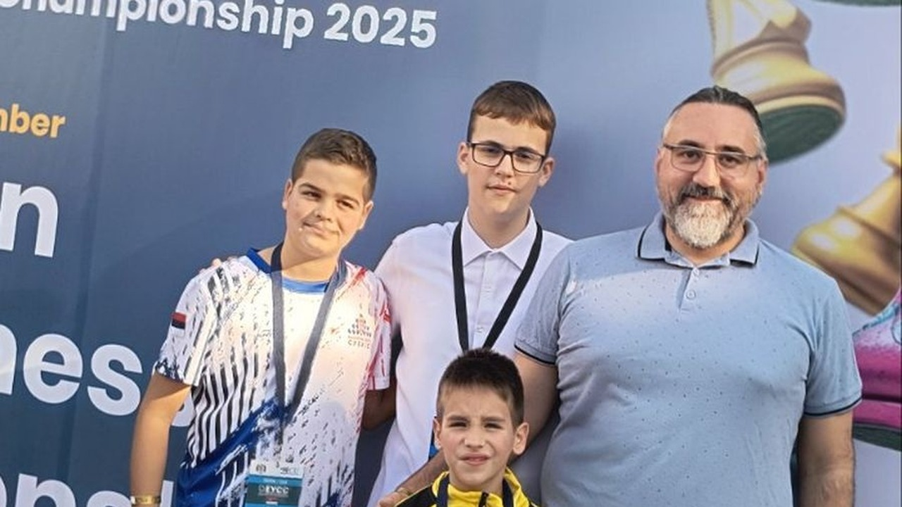 Young chess players show their medals beside an organiser