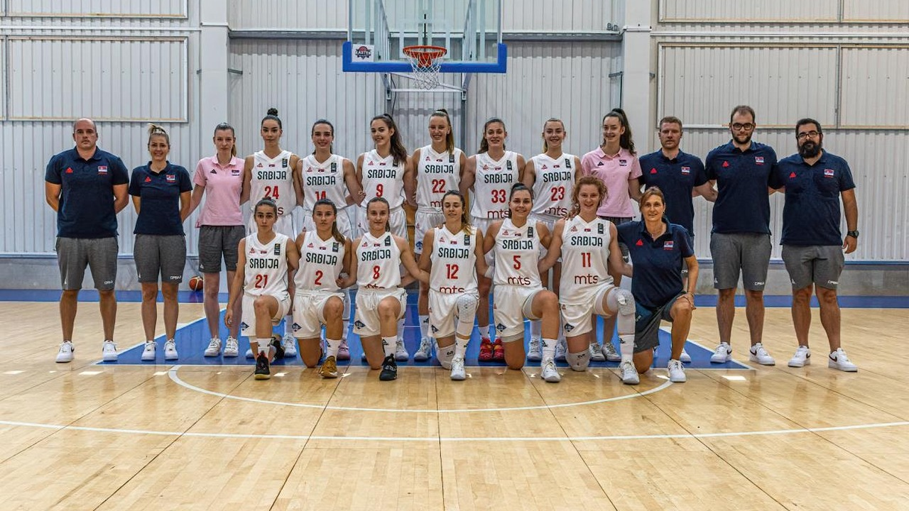 Serbia under-18 women's basketball players and coaches pose in a sports hall