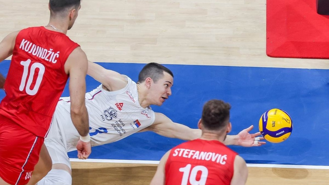 A Serbia player reaches for the ball beside a Slovenia opponent