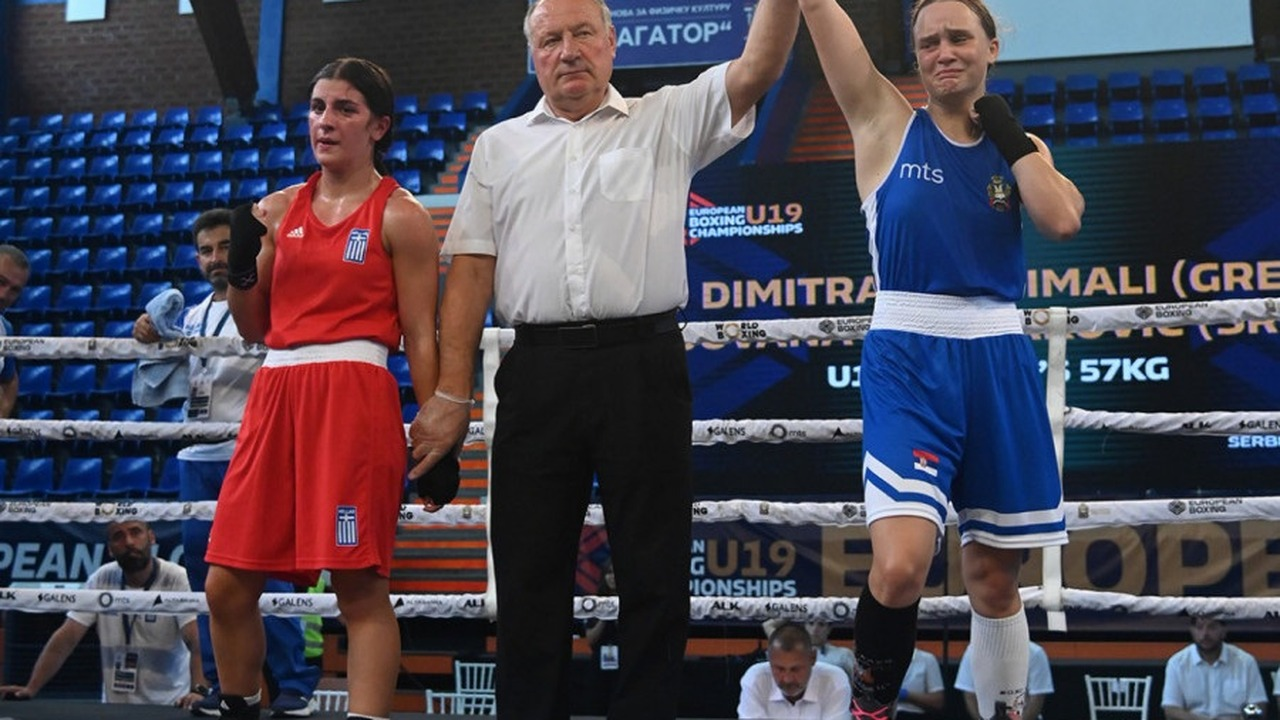 Two women boxers stand inside a boxing ring