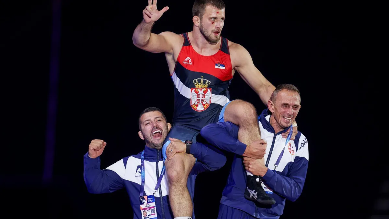 Aleksandar Komarov celebrates a wrestling victory with his coaches