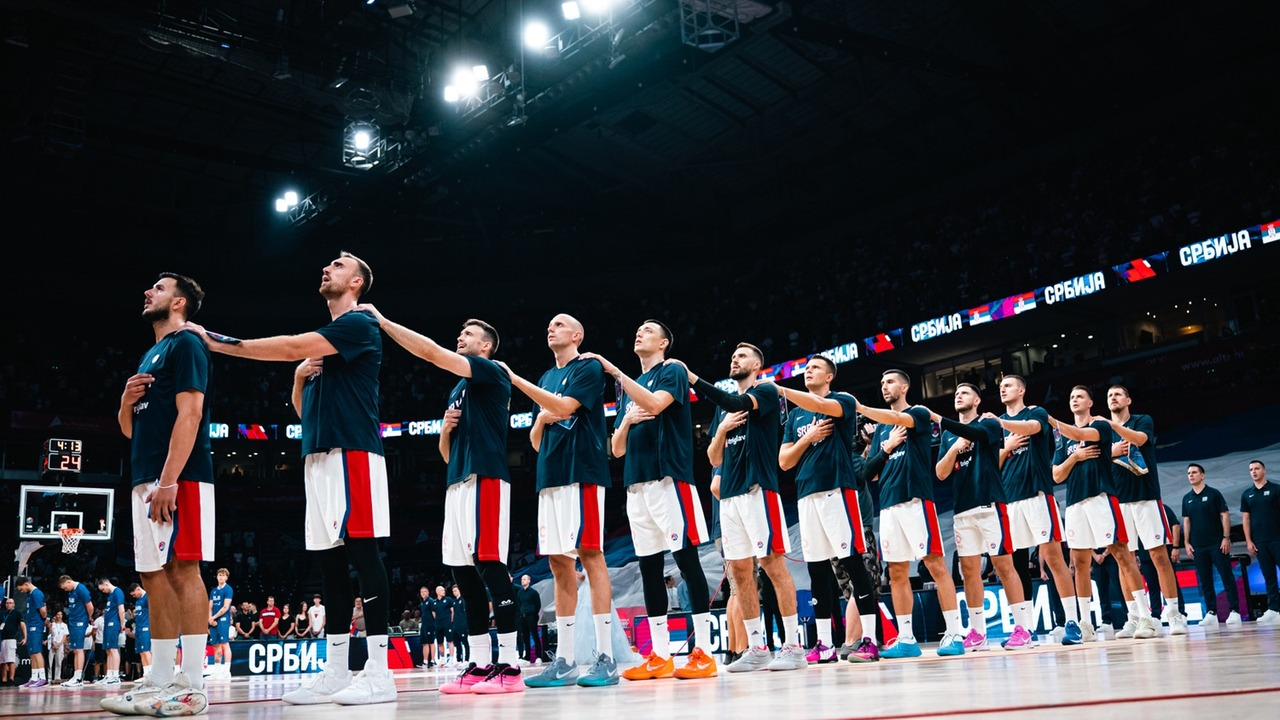 Serbia players and staff gather on the basketball court
