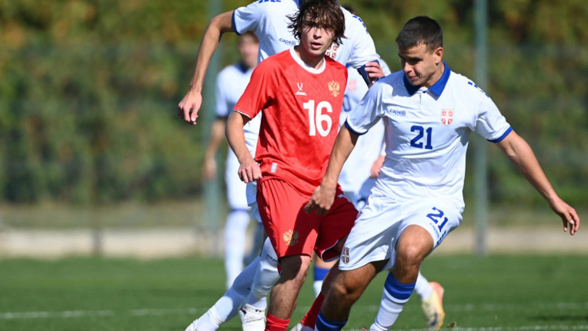 Serbian and Russian youth players contest possession during an international match