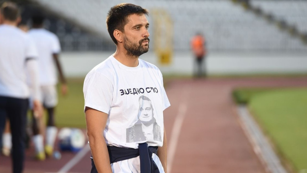 Marko Savić stoji pored fudbalskog terena u beloj majici