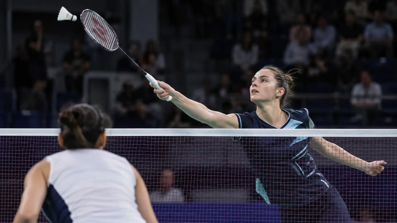 Badminton igrač preuzima lopticu iznad mreže